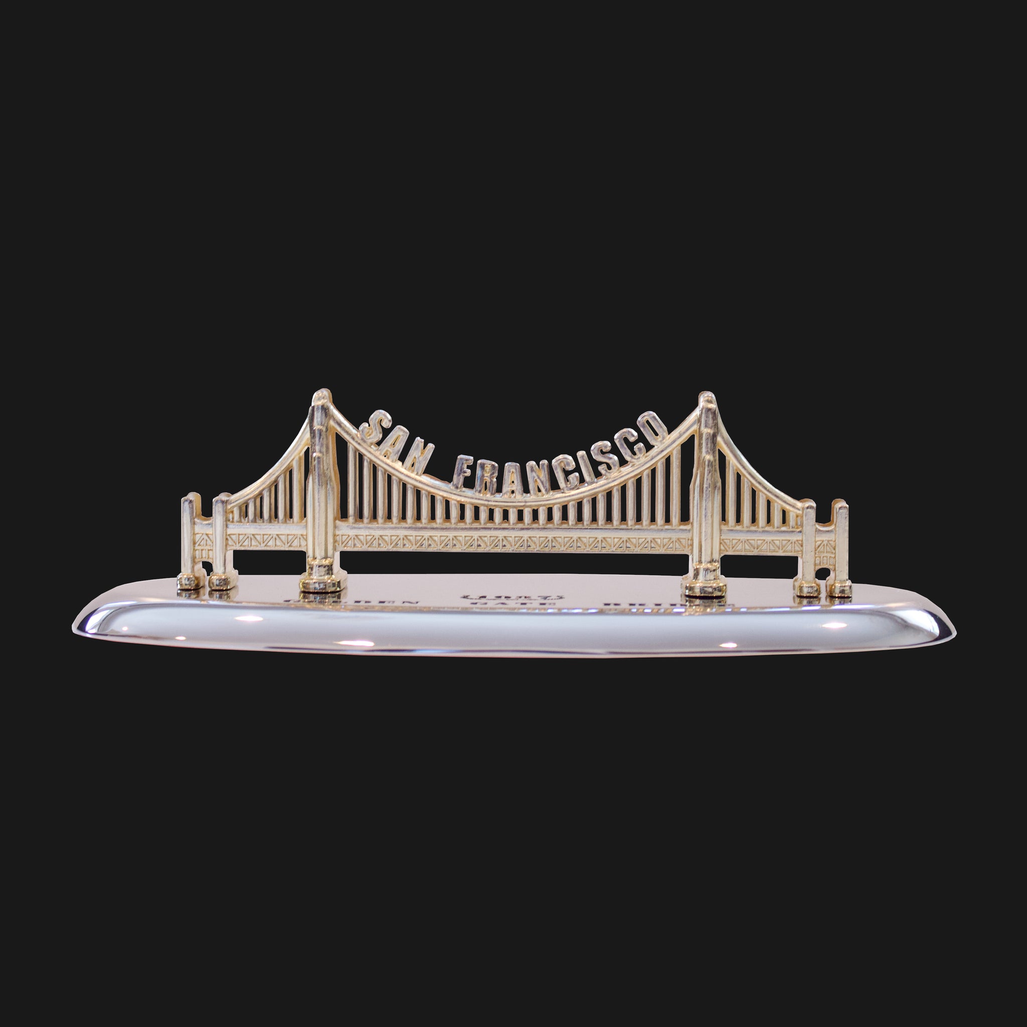 A gold color model of the Golden Gate Bridge on a stand.