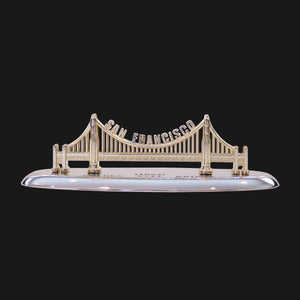 A gold color model of the Golden Gate Bridge on a stand.