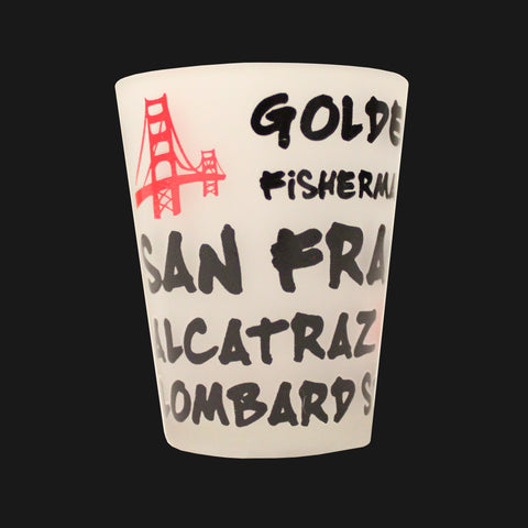 A frosted shot glass with Golden Gate Bridge, Fisherman Wharf, San Francisco, Alcatraz, Lombard Street texts printed on the side.