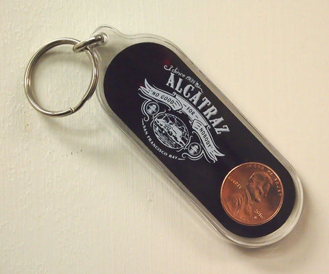 Front side view of an Oblong plastic key chain with "Alcatraz "No Good for Nobody"  logo and a Penny embedded inside