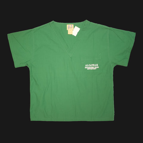 A green v-neck scrub short sleeves shirt with "Alcatraz psychiatric ward outpatient" on the left chest pocket.